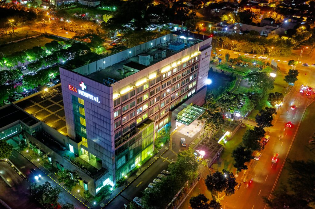 Hospital Beside Vehicle Park and Road at Night