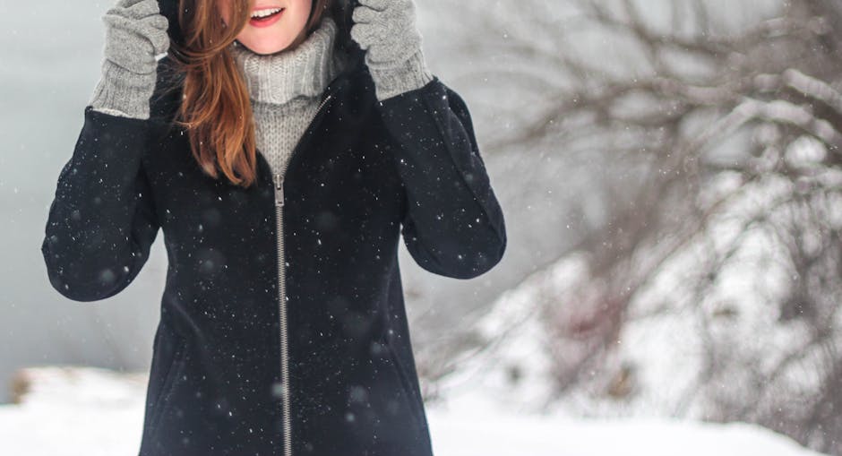 A woman enjoying a snowy winter day, dressed warmly and smiling.