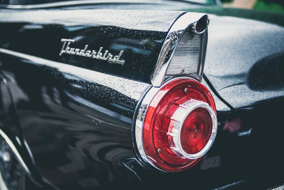 A classic Ford Thunderbird's taillight with water droplets, reflecting vintage automotive style.