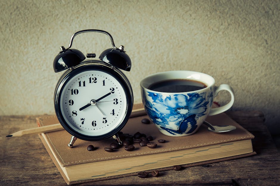 Cozy morning setup with a vintage alarm clock and floral coffee cup on a book. Perfect for capturing morning routines.