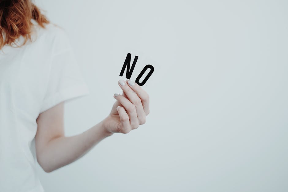 Close-up of person holding the word 'NO' in black letters on a white background, conveying a message of refusal.