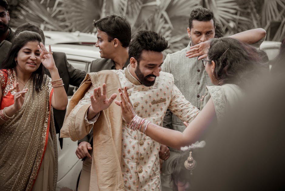 Group of happy guests dancing at a vibrant and colorful Indian wedding ceremony outdoors.